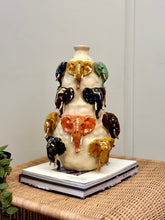 High Objects Safari Heritage Elephant Art Showpiece, a cream ceramic vase with multiple colorful elephant heads and gold tusks.