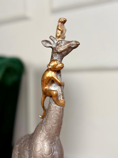 High Objects Savannah Majesty Showpiece sculpture of a giraffe with a monkey climbing its neck and a small animal on its head. Polyresin, dark finish.
