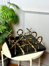 High Objects Sculpted Gold Tic-Tac-Toe Set with gold-finished iron X and O pieces on a black MDF board.