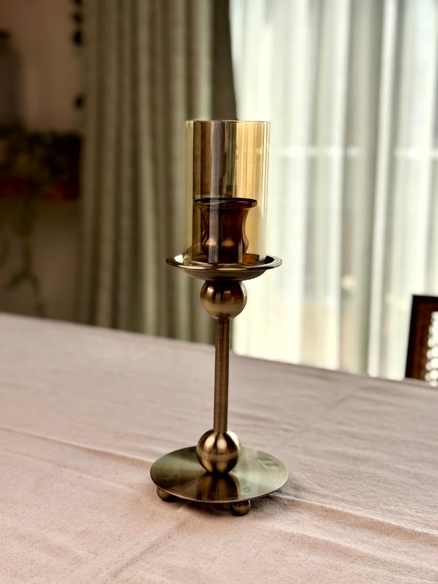 High Objects Seren Column Candle Stand Set, antique brass metal with amber glass hurricane cover and sphere detail.