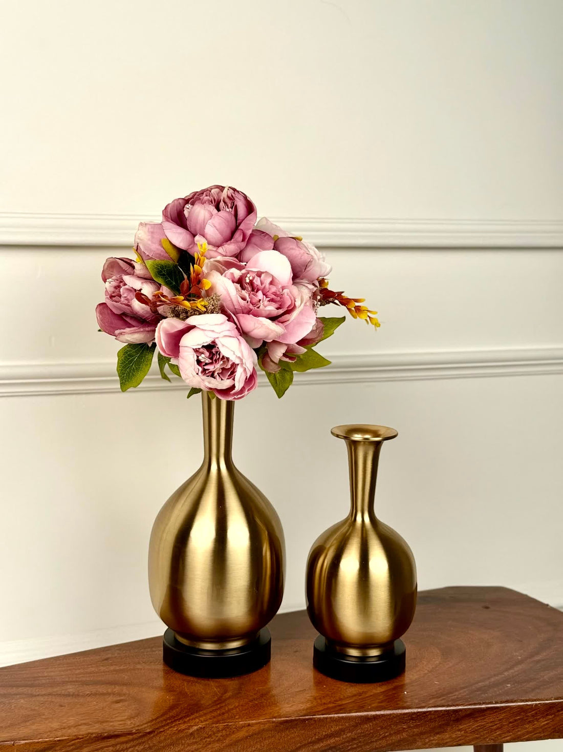 High Objects Solara Sculpted Vase set in brushed gold metal with rounded bodies and slender necks. One vase holds pink peonies.