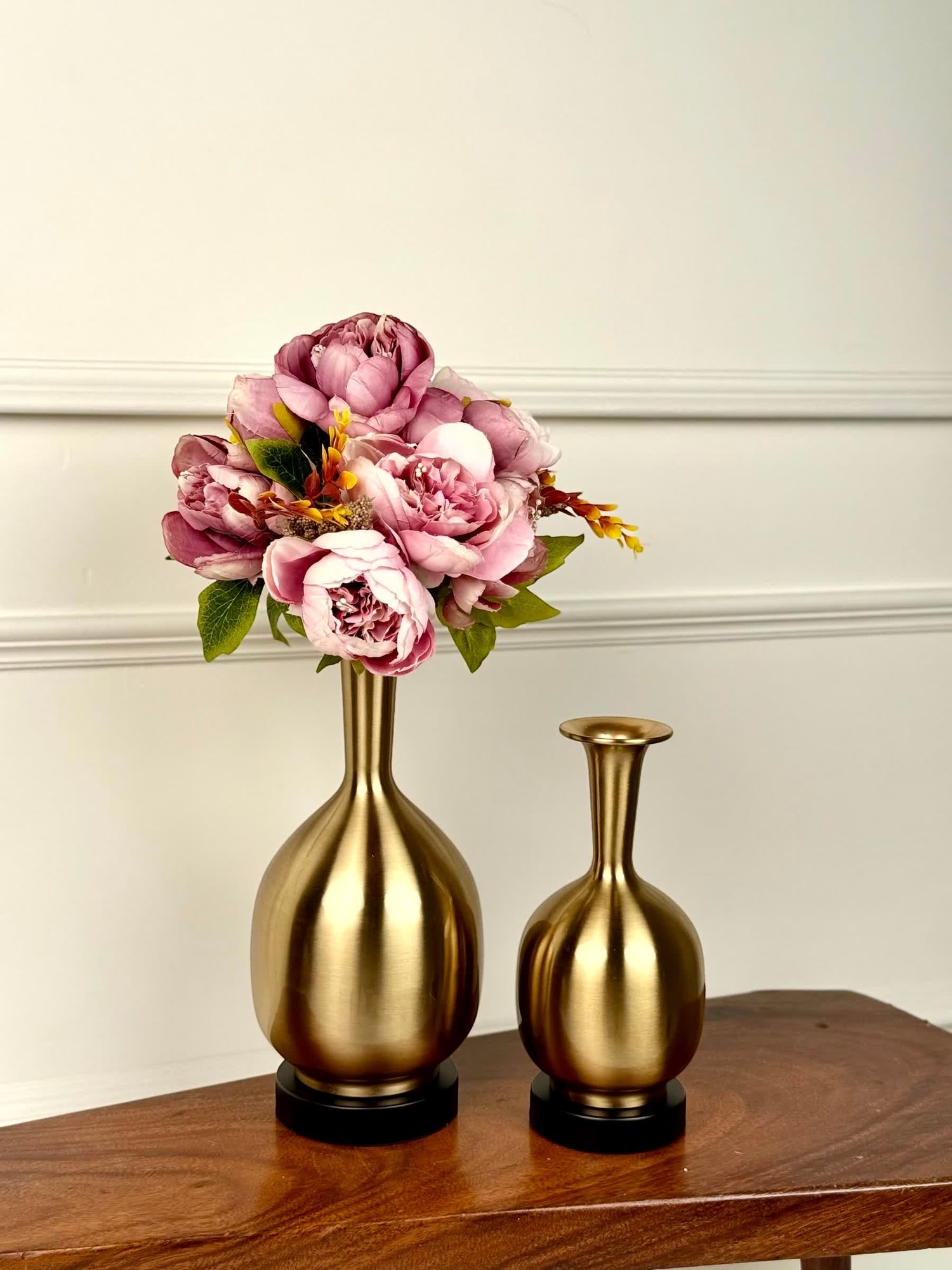High Objects Solara Sculpted Vase set in brushed gold metal with rounded bodies and slender necks. One vase holds pink peonies.
