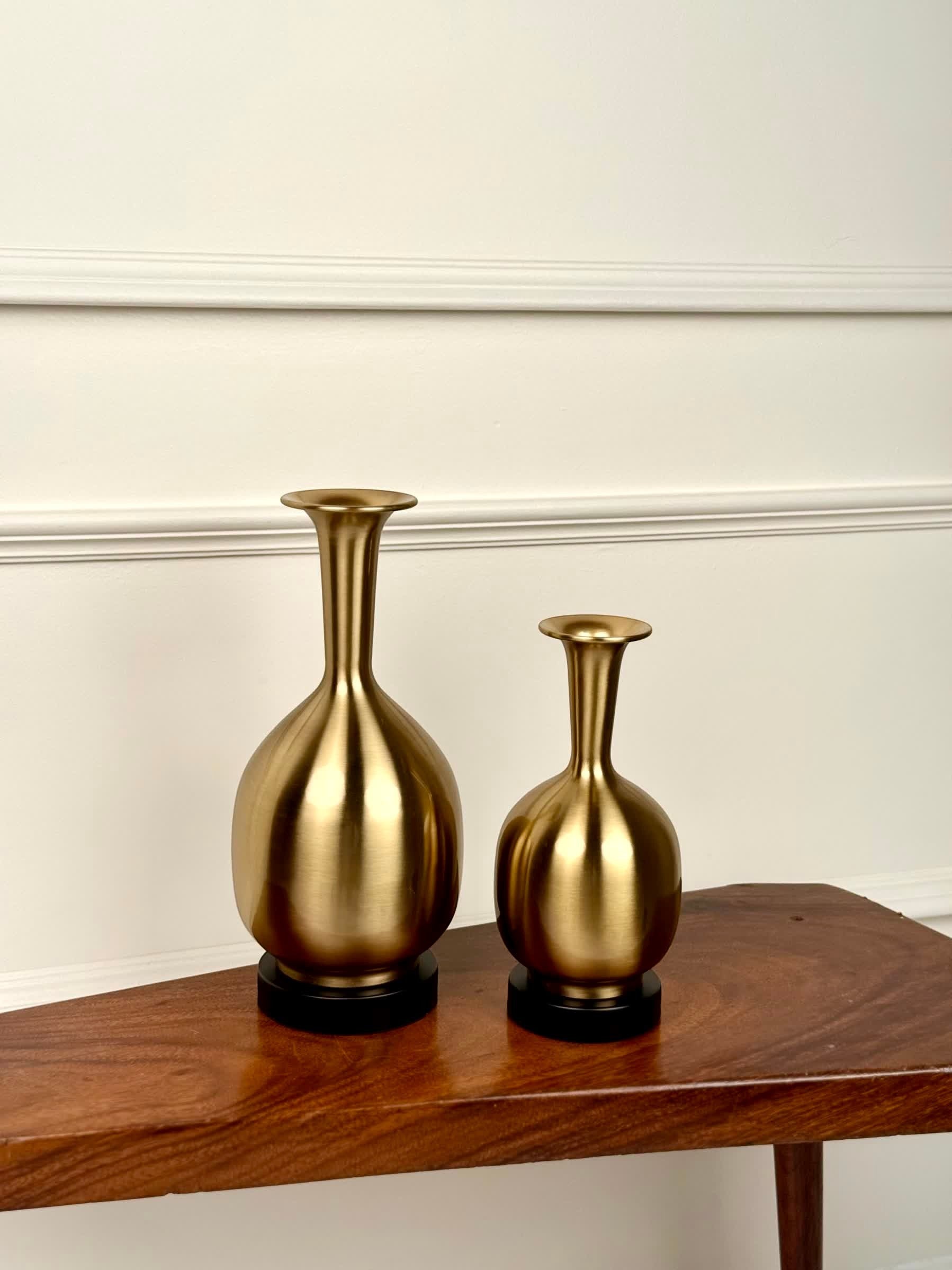 High Objects Solara Sculpted Vase, gold metallic finish, rounded body, slender neck, flared rim, on a wooden table.