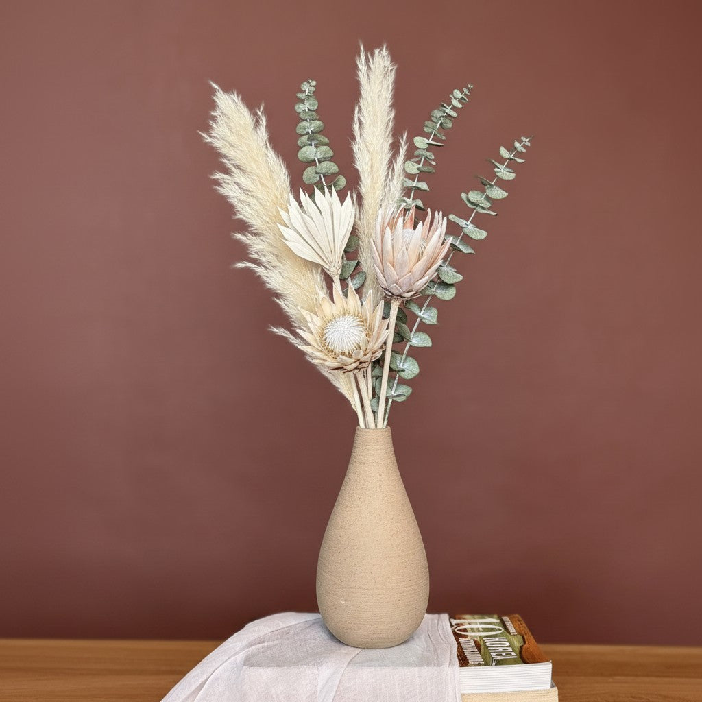 High Objects Solora Vase, a teardrop-shaped natural clay vase with a textured finish, holding dried bunny tail grass in tan and mint green.