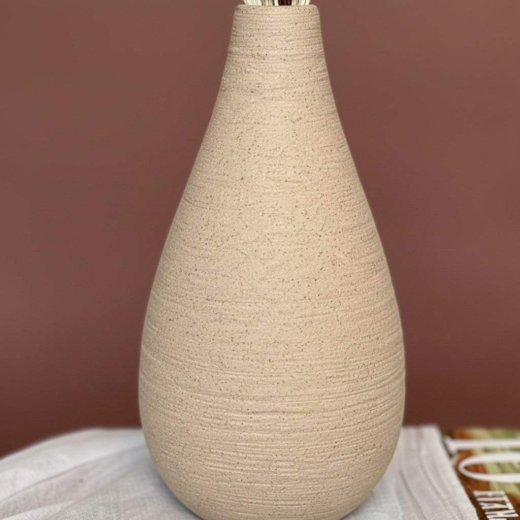 High Objects Solora Vase, handcrafted natural clay with teardrop silhouette, holding dried pampas grass and eucalyptus.