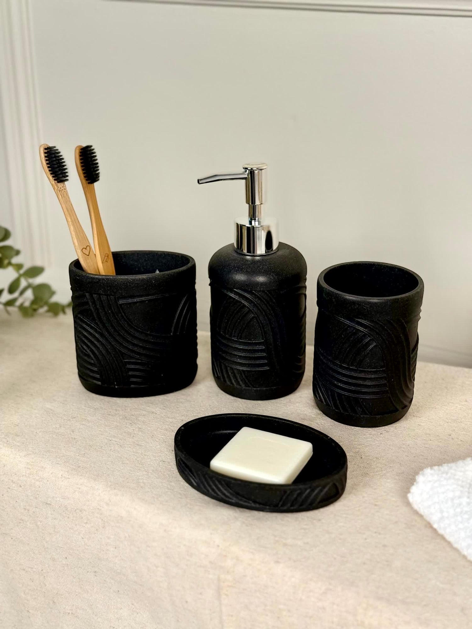 High Objects Stratacurve black bathroom accessory set with soap dish, dispenser, and toothbrush holder featuring carved grooves.