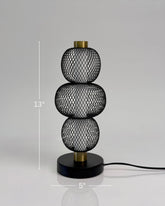 High Objects Trinity Slim Mesh Table Lamp with stacked spherical black mesh shades and brass accents.