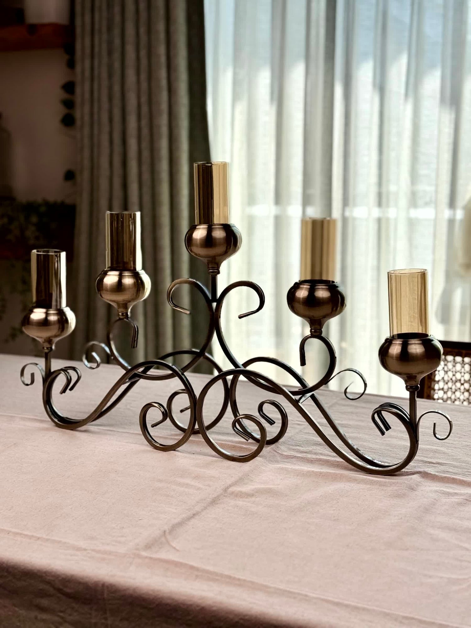 High Objects Valencia Scroll Five-Arm Candle Stand with bronze finish and amber glass holders.