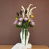 High Objects Volara Vase in pale green ceramic with twisting lines, holding a floral arrangement.