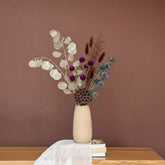 High Objects beige ceramic vase with wavy rim, holding dried eucalyptus and pampas grass.