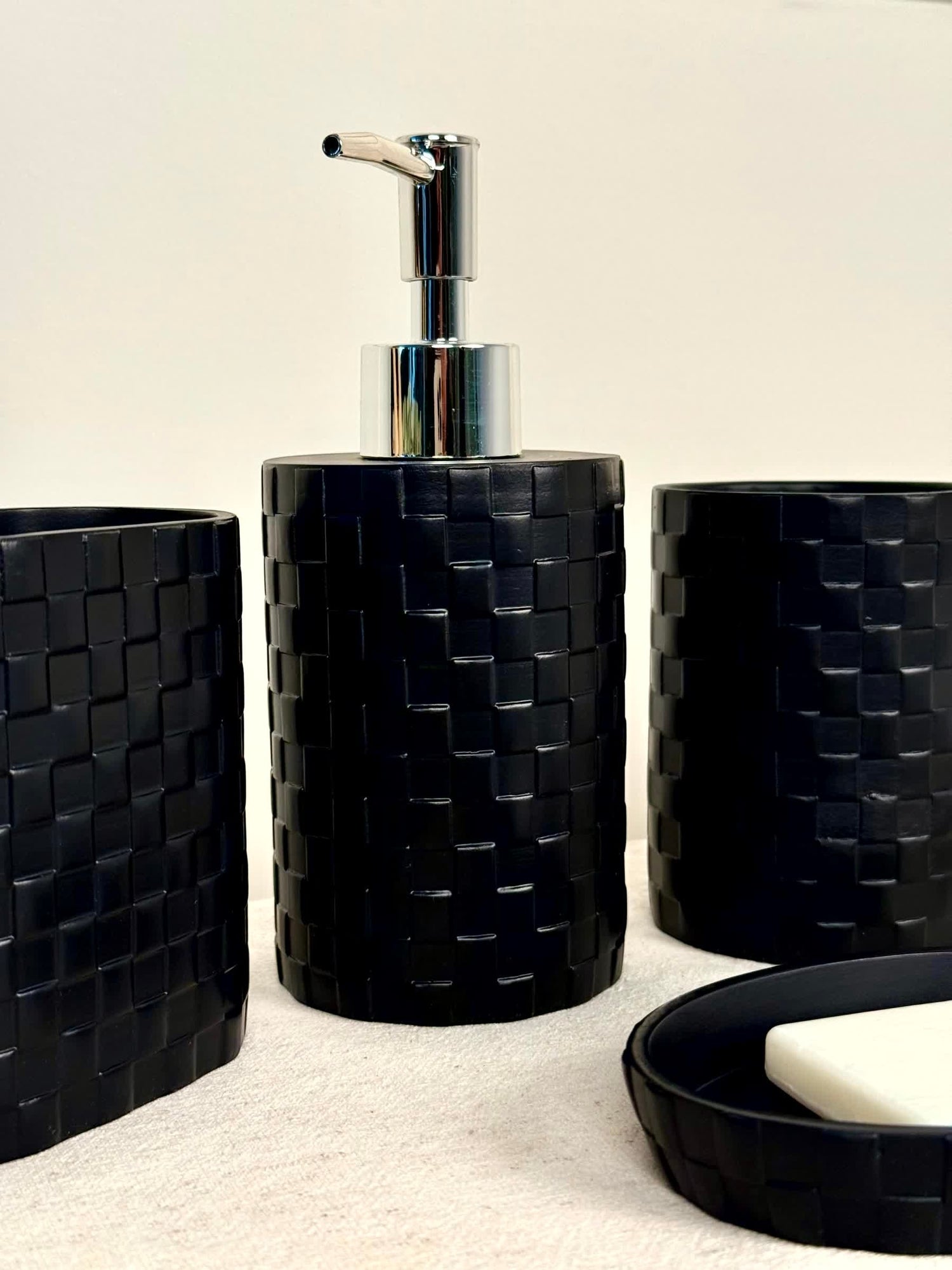 High Objects Weaveform black bathroom accessory set with woven texture, includes soap dispenser, cup, and soap dish.