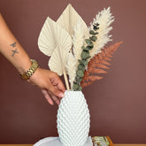 High Objects Arisca Vase, white ceramic with textured wave pattern, holding dried botanicals. Modern decor.