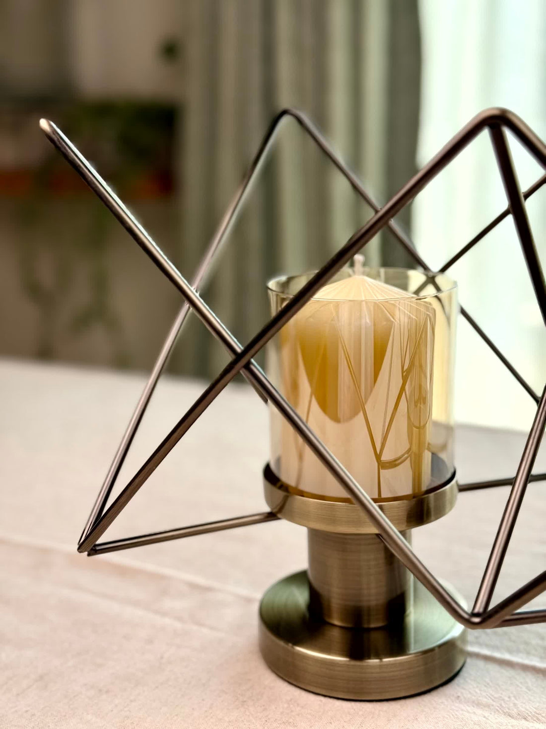 High Objects Zigzag Geo candle stand set with bronze metal frame and amber glass holder, holding a cream candle.