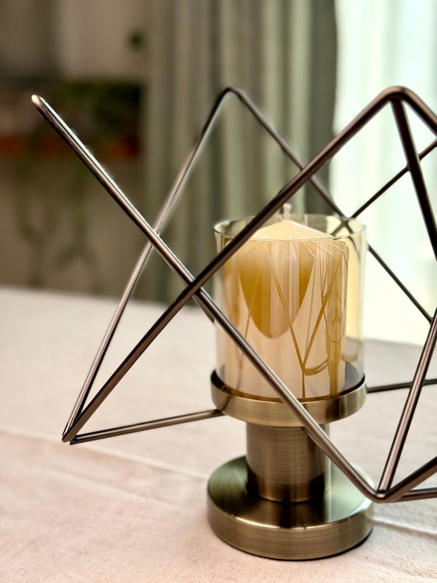High Objects Zigzag Geo candle stand set with bronze metal frame and amber glass holder, holding a cream candle.