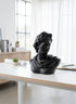 High Objects black matte bust of Apollo, a classical sculpture with intricate hair and draped clothing, displayed on a white desk.