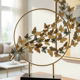 High Objects gold metal circular sculpture with a branch of butterflies in varying shades of gold and blue.