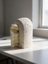 High Objects Olea white tissue box with a rough stone-like texture and a modern arched design on a table.